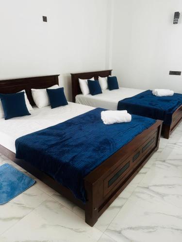 two beds with blue sheets in a room at Seven Crest Hotel Anuradhapura in Anuradhapura