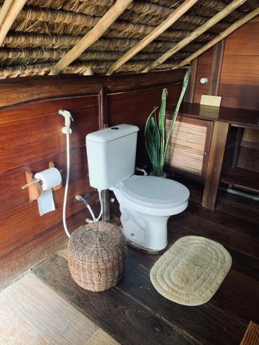 a bathroom with a toilet and a plant in it at Casa Tassimirim in Ilha de Boipeba