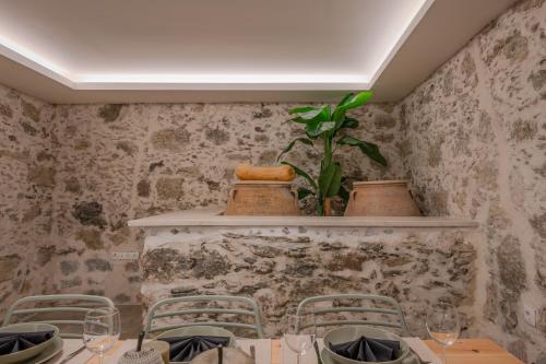 a table with chairs and a plant on a wall at Casa Karinea - Serene Stone House Retreat in Áyios Vasílios