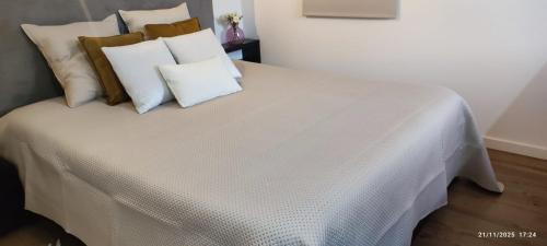 a white bed with pillows on top of it at Casa da Pedra - Alvados, Porto de Mós in Alvados