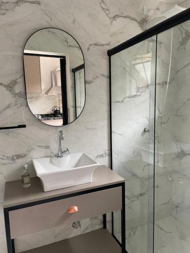 a bathroom with a sink and a mirror at Murakami Pousada in Itanhaém