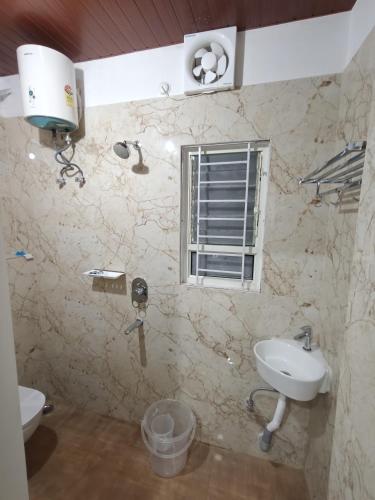 a bathroom with a sink and a toilet and a window at Hoppin Homestay in Guwahati