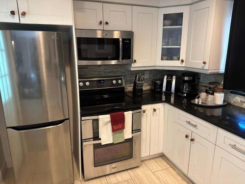 Cape Coral Beach House في كيب كورال: مطبخ مع أجهزة ستانلس ستيل ودواليب بيضاء