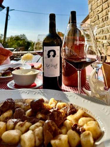 a table with a plate of food and a bottle of wine at San Mauro Countryside Retreat with Restaurant & Wine Cellar in Momjan