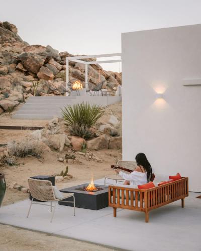 a woman sitting on a bench next to a fire pit at Bolder House By The Cohost Company in Joshua Tree
