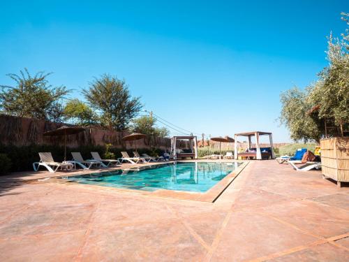 una piscina con tumbonas y sillas en Maison Daouia, en Marrakech