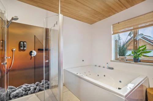 une salle de bain avec baignoire et douche en verre dans l'établissement Fewo Mit Herz Und Holz Penzing, à Penzing