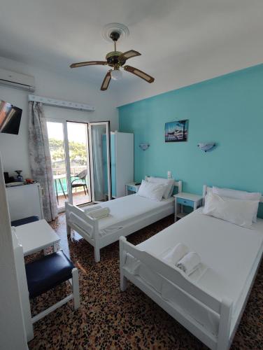 a bedroom with two beds and a ceiling fan at Magdalini in Votsi