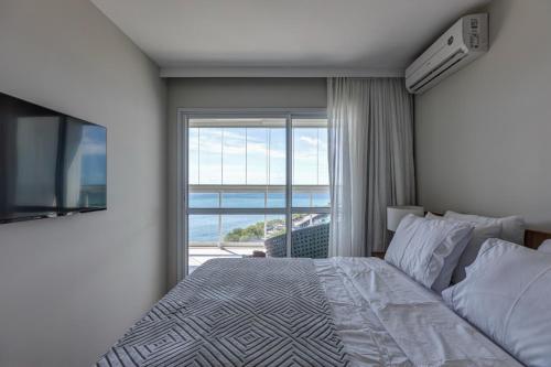 a bedroom with a bed and a large window at Aconchegante apartamento em Cloc Marina Residence in Salvador