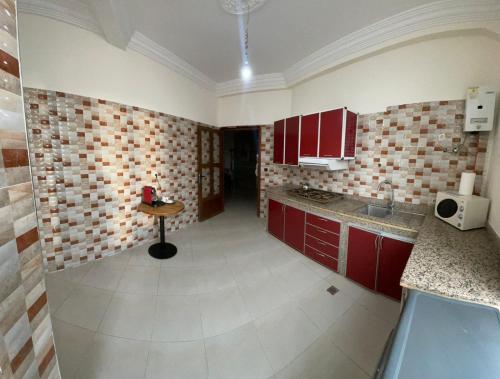 - une cuisine avec des placards rouges et une table dans l'établissement appartement chic, calme et bien équipé, à Meknès