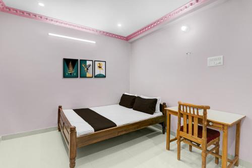 a bedroom with a bed and a desk and a chair at SPOT ON Hotel Parvati Resort in Suitha