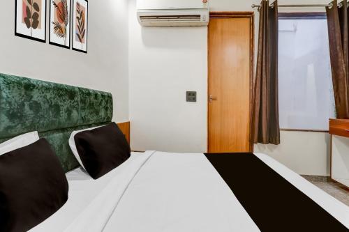 1 dormitorio con cama blanca y cabecero verde en Hotel O Riwaz Inn, en Gwalior