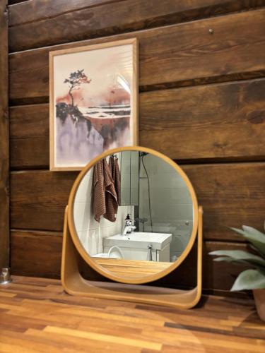 a bathroom with a round mirror on a wooden wall at Villa Hirsipirtti in Rovaniemi