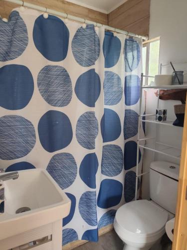 a bathroom with a toilet and a blue and white shower curtain at Cabaña Campestre in El Cerrillo
