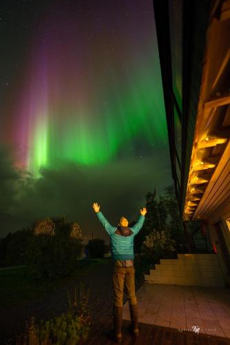 a man standing in front of a house with his arms up at Northern Lights Apartment in Mortenhals