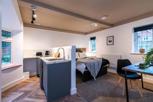 a room with a bed and a kitchen with a sink at The Coach House, Gatwick in Horley