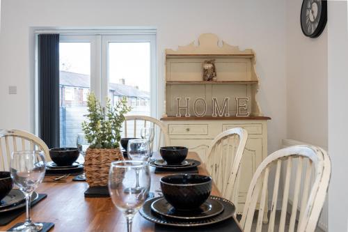 a dining room table with chairs and a home sign at Modern 5-Bed Home EV City Centre 10 min in Manchester