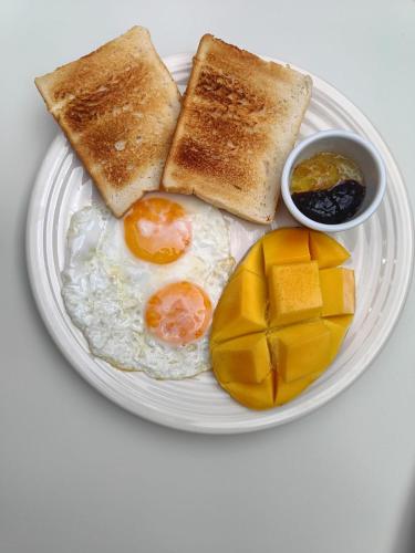 um prato com ovos e torradas e uma tigela de frutas em La Maison - Siquijor em Siquijor