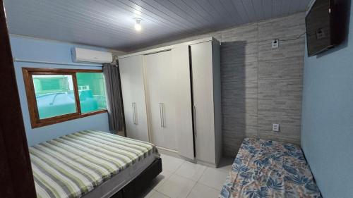 una piccola camera da letto con un letto e una finestra di Karina Saraiva a Palhoça