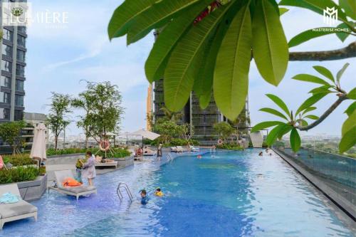 une piscine dans un hôtel avec des gens dans l'eau dans l'établissement The Lumiere Riverside Apartment View City, à Hô-Chi-Minh-Ville