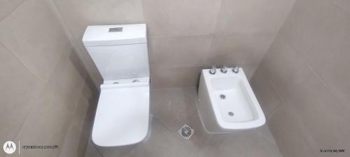 a bathroom with a white toilet and a sink at Lihuel AG in Alta Gracia