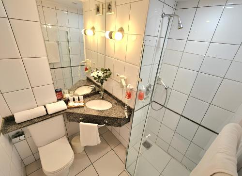 a bathroom with a shower and a toilet and a sink at Hotel Santoni in Guarapuava