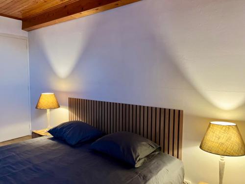 un lit avec deux oreillers bleus et deux lampes dans l'établissement Le Petit Four à Pain - Maison 4 personnes à la Campagne, à Neuvicq-Montguyon