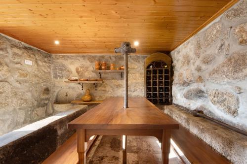 ein Holztisch in einem Raum mit Steinwänden in der Unterkunft Quintinha De Pinouco in Miomães