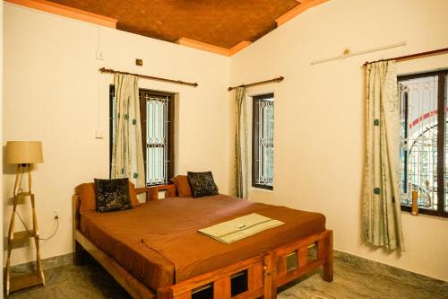 a bedroom with a wooden bed with windows at Kulture KonnectT Kurakanni in Varkala