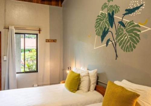 Un dormitorio con una cama con almohadas amarillas y una ventana. en Monteverde The Lodge, en Monteverde