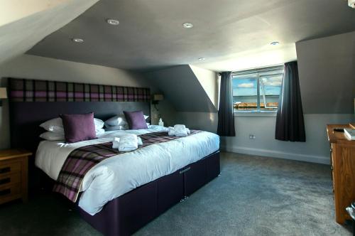um quarto com uma cama grande e almofadas roxas em Lochside hotel em Bowmore