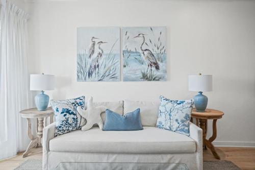 a living room with a white couch with blue pillows at Quiet Harbor Condo-Private Balcony-Relaxing Stay in Pass Christian