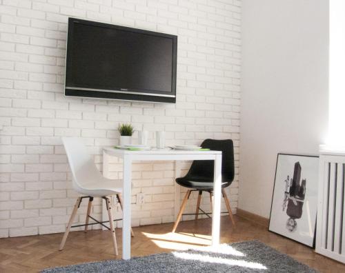 mesa blanca con 2 sillas y TV en la pared en Studio in heart of Warsaw, en Varsovia