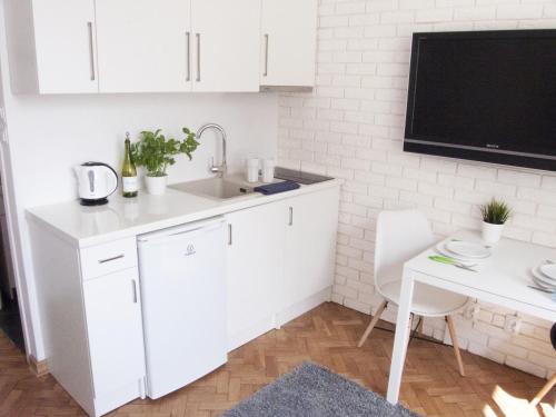 a kitchen with white cabinets and a tv on a wall at Studio in heart of Warsaw in Warsaw