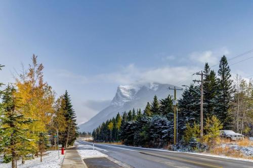 a snowy road with a snow covered mountain in the background at Free Arcade Delightful Stay in Rocky Mountains in Dead Man's Flats