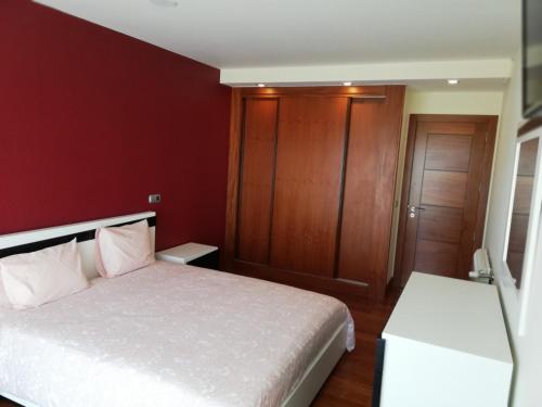 een slaapkamer met een wit bed en een rode muur bij Casa Do Chino in Outeiro
