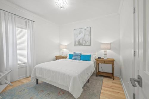 a white bedroom with a bed with blue pillows at Extended Stay Friendly-Full Kitchen & Laundry in Pass Christian