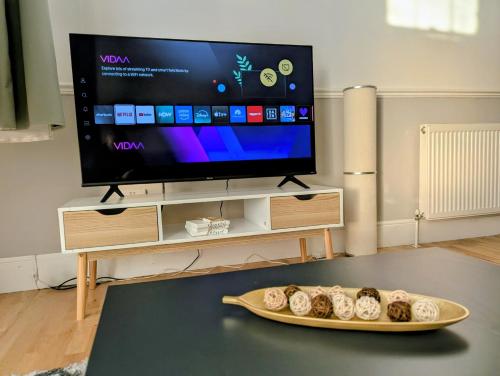 a living room with a tv and a tray of donuts at 2 Bedroom House with Garden and Free Parking -10 min to London Bridge and near Lewisham Hospital in Lewisham