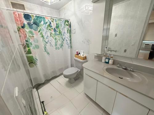 a white bathroom with a toilet and a sink at Paradise Palms in San Juan