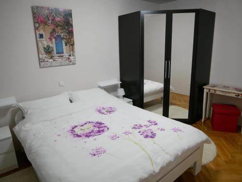 ein Schlafzimmer mit einem weißen Bett mit lila Blumen darauf in der Unterkunft Queen's gate in Zagreb