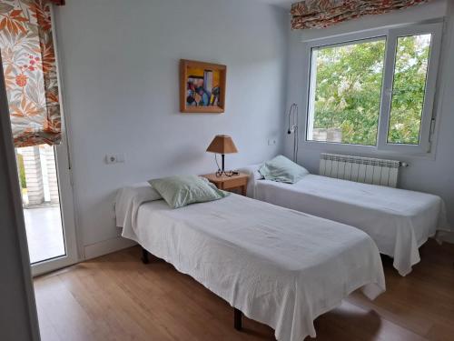 two beds in a room with two windows at La Pabla in Colunga
