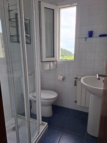 a bathroom with a toilet and a sink and a window at La Pabla in Colunga