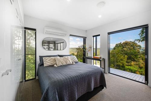a bedroom with a bed and large windows at Magical Malindi, Montville. QLD in Montville