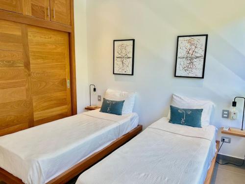 two beds in a room with white sheets and blue pillows at Villa Hazel in Las Terrenas
