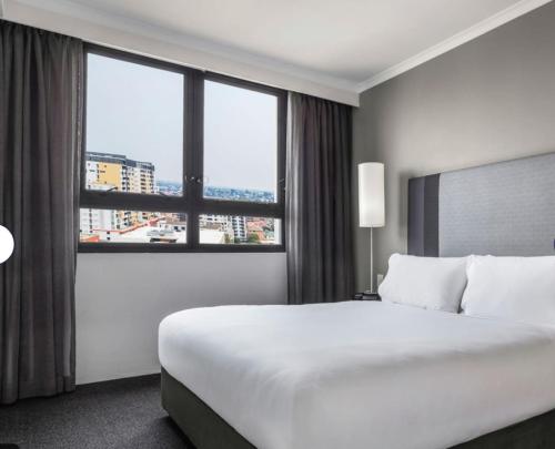 Opulent one bedroom apartment in parramatta. في سيدني: غرفة فندق بها سرير ونافذة كبيرة