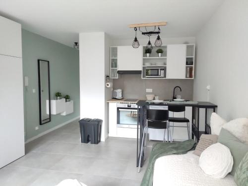 eine kleine Küche und ein Wohnzimmer mit einem Tisch und einer Couch in der Unterkunft Studio Cosy, résidence sécurisée, parking privé in Pau