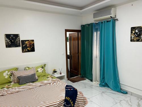 ein Schlafzimmer mit einem Bett und einem Fenster mit blauen Vorhängen in der Unterkunft LUXES Appartement in Dakar