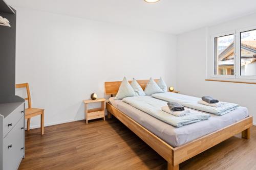 a bedroom with a bed with white walls and a window at Chuenislodge1 Neu, grosse Terrasse & Designerofen, prächtige Aussicht in Adelboden