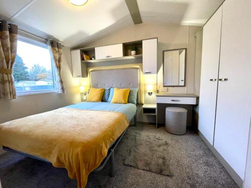 Un dormitorio con una cama con almohadas amarillas y una ventana. en Billing Aquadrome - Bird Lake View, en Great Billing