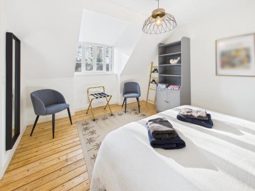 a white bedroom with two chairs and a bed at Loki Rivoli Cottage in Locquirec